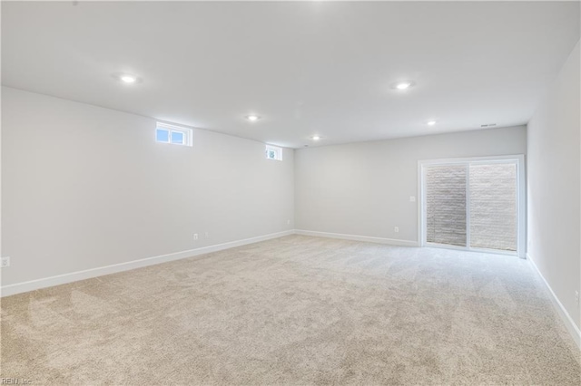 below grade area featuring recessed lighting, light colored carpet, visible vents, and baseboards