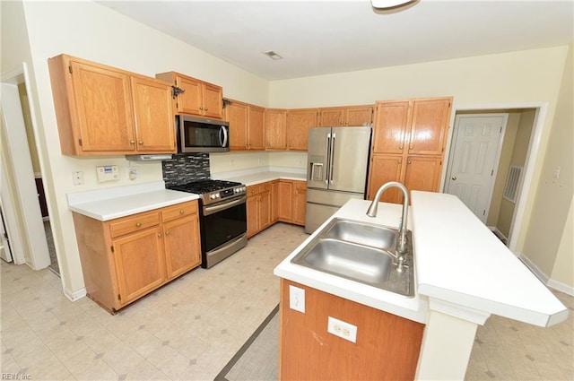 kitchen featuring light countertops, appliances with stainless steel finishes, a sink, and a kitchen island with sink