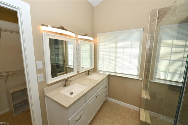 bathroom with a walk in closet, a sink, and double vanity