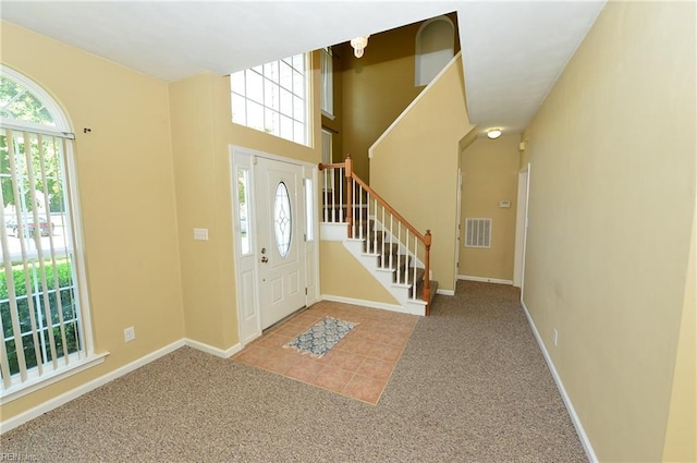 carpeted entryway featuring visible vents, plenty of natural light, baseboards, and stairs