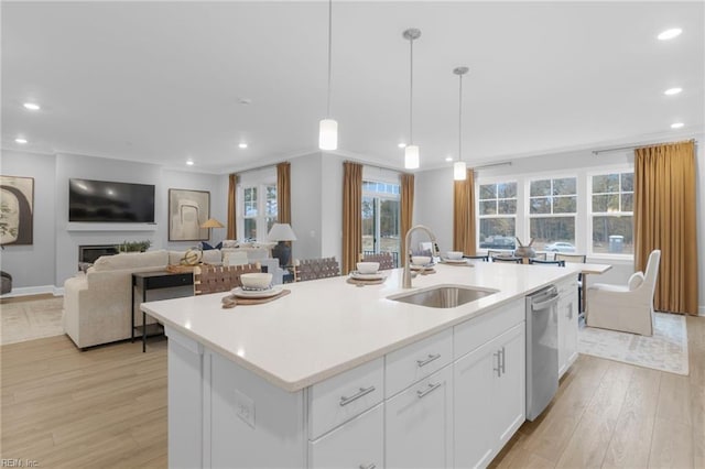 kitchen with dishwasher, a sink, a kitchen island with sink, and white cabinetry