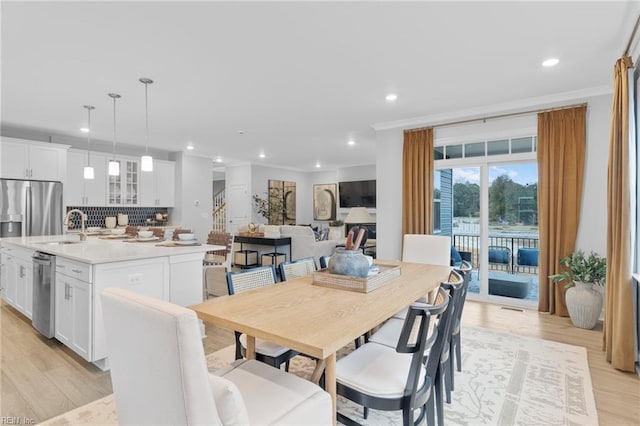 dining space featuring light wood-style floors, recessed lighting, crown molding, and stairs