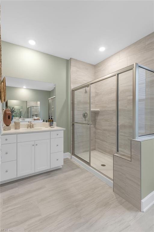 bathroom featuring a stall shower, baseboards, and vanity