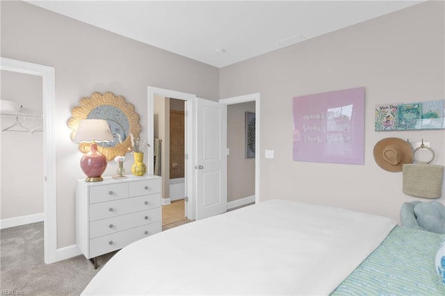 bedroom featuring light carpet, a spacious closet, baseboards, and a closet