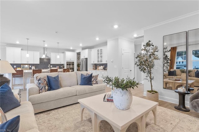 living area featuring crown molding, recessed lighting, visible vents, light wood-type flooring, and baseboards