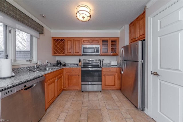 kitchen featuring brown cabinetry, ornamental molding, stainless steel appliances, and a sink