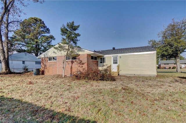 rear view of property featuring brick siding, a lawn, and central air condition unit