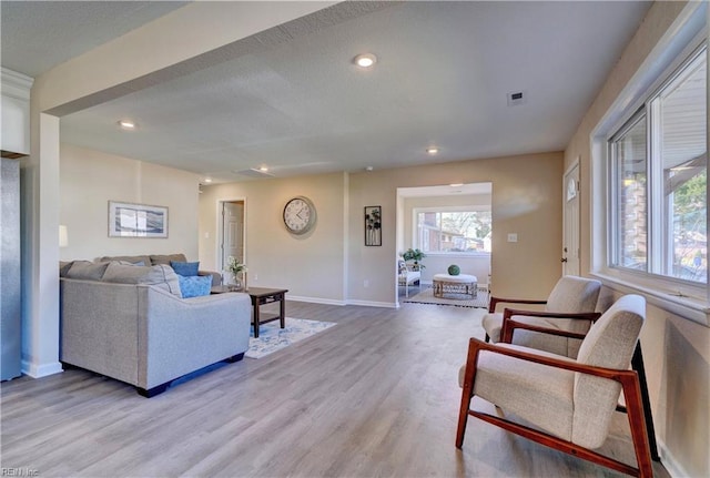 living room with recessed lighting, baseboards, visible vents, and light wood finished floors