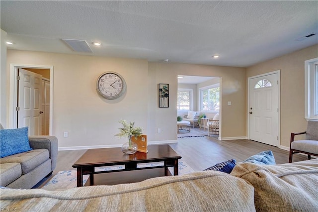 living room with light wood-style flooring, visible vents, and baseboards