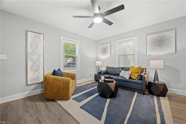 living area with a ceiling fan, baseboards, and wood finished floors