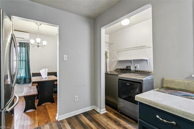 kitchen with light countertops, hanging light fixtures, freestanding refrigerator, washer and clothes dryer, and a wall mounted air conditioner