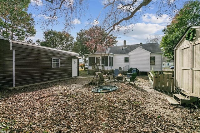 rear view of house with a sunroom, an outdoor fire pit, a storage shed, and an outbuilding