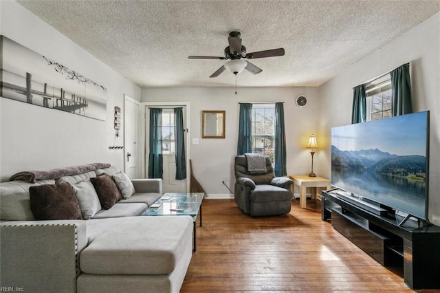 living room featuring ceiling fan, a textured ceiling, baseboards, and wood finished floors