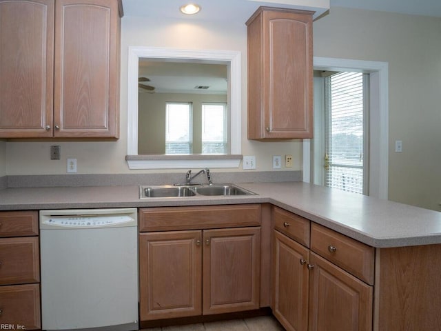 kitchen featuring a peninsula, a sink, light countertops, a wealth of natural light, and dishwasher