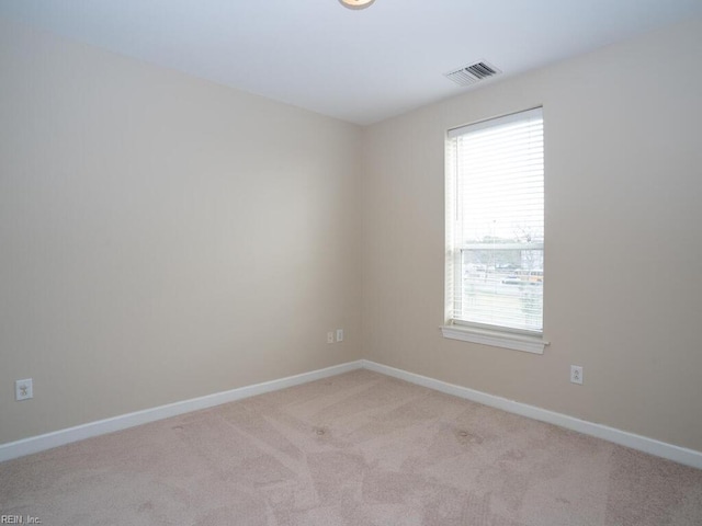 unfurnished room with baseboards, visible vents, and light colored carpet