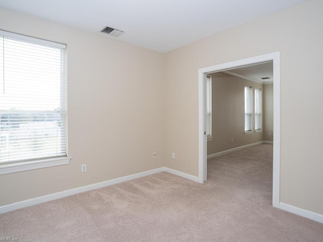 unfurnished room featuring light carpet, visible vents, and baseboards