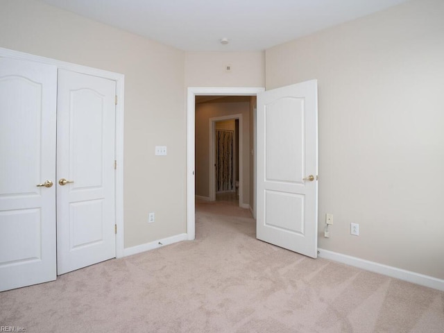 unfurnished bedroom with light colored carpet and baseboards