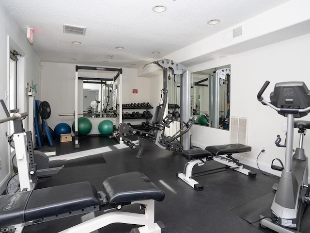 workout area featuring visible vents, baseboards, and a textured ceiling