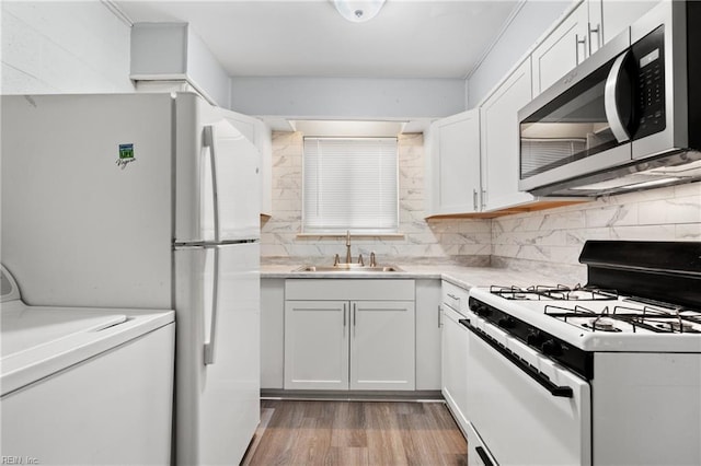 kitchen featuring light countertops, white appliances, a sink, and white cabinets