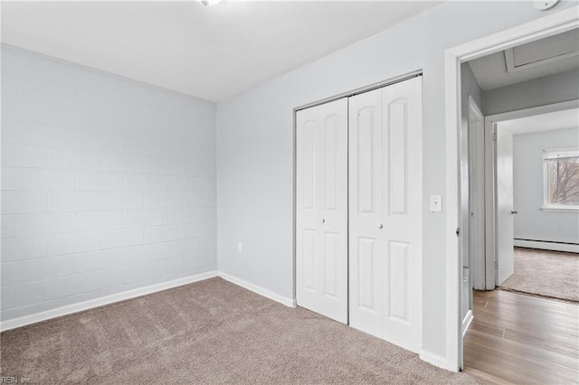 unfurnished bedroom featuring carpet floors, a baseboard radiator, a closet, and baseboards