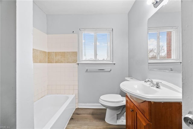 full bath featuring toilet, wood finished floors, vanity, baseboards, and a bathtub