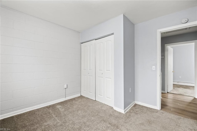 unfurnished bedroom featuring light carpet, baseboards, and a closet