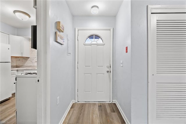 doorway featuring light wood-style floors and baseboards