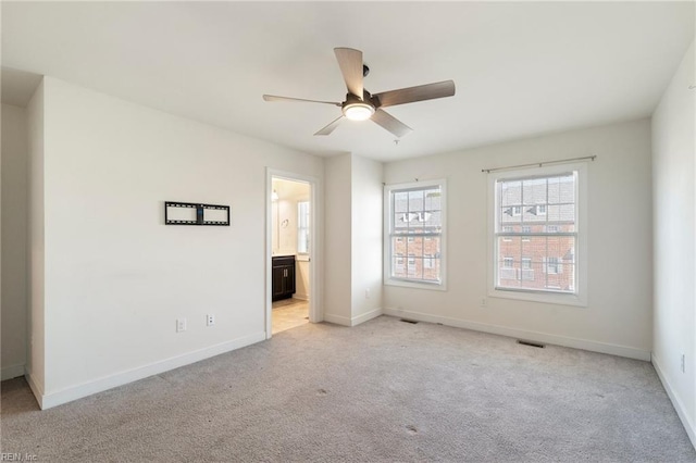 unfurnished bedroom with a ceiling fan, baseboards, connected bathroom, and light colored carpet