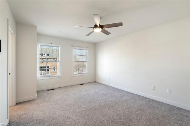 empty room featuring visible vents, baseboards, a ceiling fan, and light colored carpet