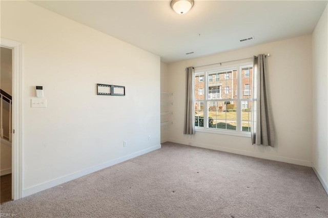 carpeted spare room featuring visible vents and baseboards