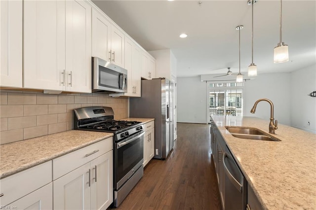 kitchen featuring stainless steel appliances, white cabinets, a sink, and hanging light fixtures