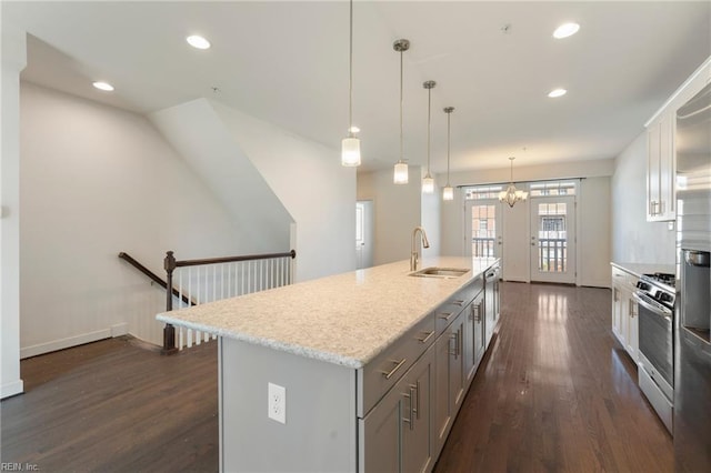 kitchen featuring an island with sink, gas stove, a sink, and decorative light fixtures