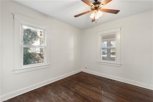 unfurnished room with dark wood-style floors, a ceiling fan, visible vents, and baseboards