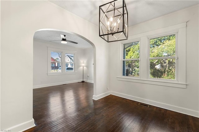 unfurnished dining area with arched walkways, dark wood-type flooring, visible vents, and baseboards