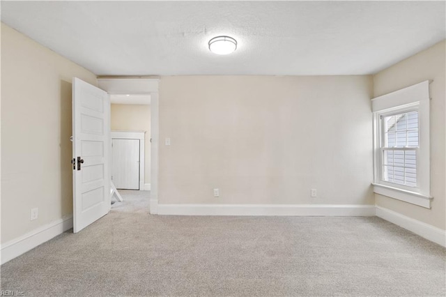 unfurnished room featuring light carpet and baseboards