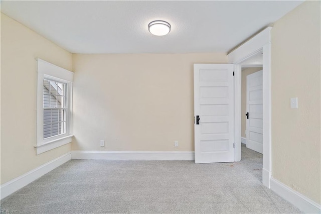 unfurnished room with baseboards and light colored carpet