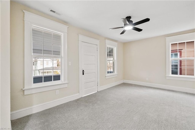 carpeted empty room featuring baseboards, visible vents, and a wealth of natural light