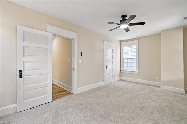 empty room featuring a ceiling fan, light carpet, visible vents, and baseboards