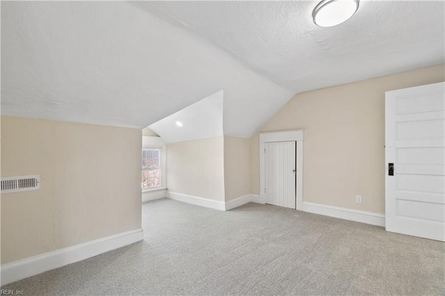 additional living space featuring baseboards, vaulted ceiling, and light colored carpet