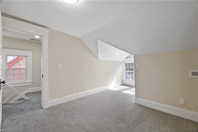 additional living space with lofted ceiling, baseboards, visible vents, and carpet