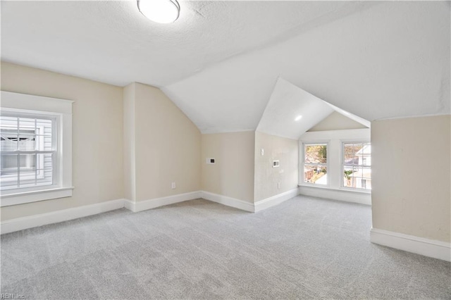 bonus room featuring lofted ceiling, light carpet, a textured ceiling, and baseboards