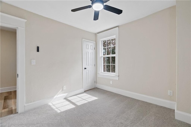 spare room featuring baseboards, ceiling fan, and light colored carpet