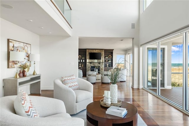 living area with a large fireplace, baseboards, wood finished floors, and a healthy amount of sunlight