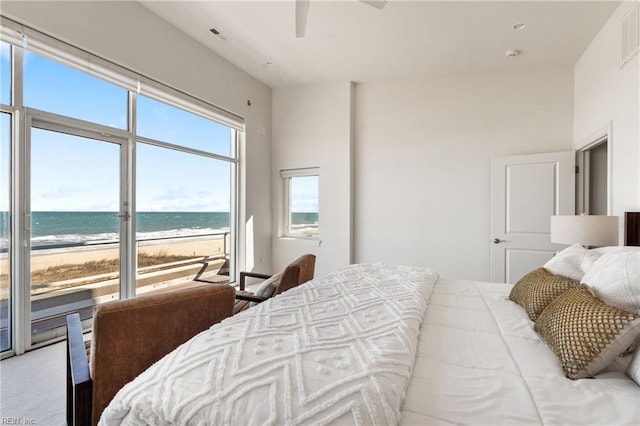 bedroom featuring ceiling fan, a beach view, a water view, visible vents, and access to outside