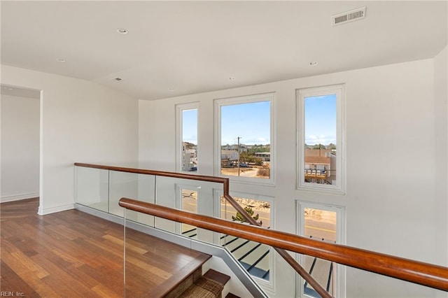 corridor with baseboards, visible vents, stairway, wood finished floors, and recessed lighting