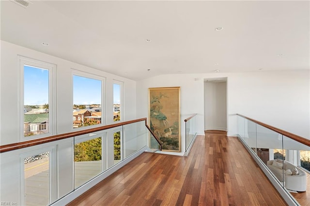 hall featuring recessed lighting, plenty of natural light, wood finished floors, and an upstairs landing