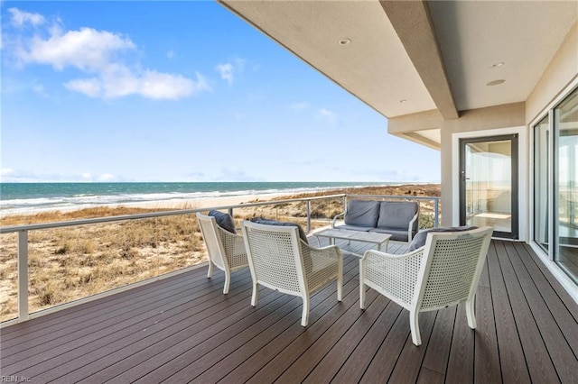 wooden terrace with outdoor lounge area, a water view, and a view of the beach