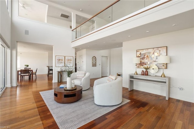 living room featuring a high ceiling, visible vents, dark wood finished floors, and baseboards