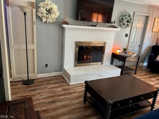 living area with dark wood-type flooring, a fireplace, and baseboards