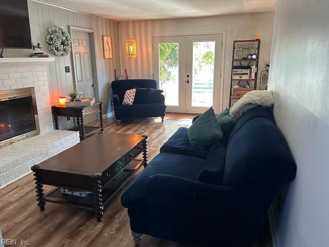 living room with a brick fireplace, french doors, and wood finished floors